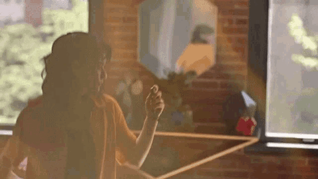 a woman is standing in front of a window in a room holding something in her hand .