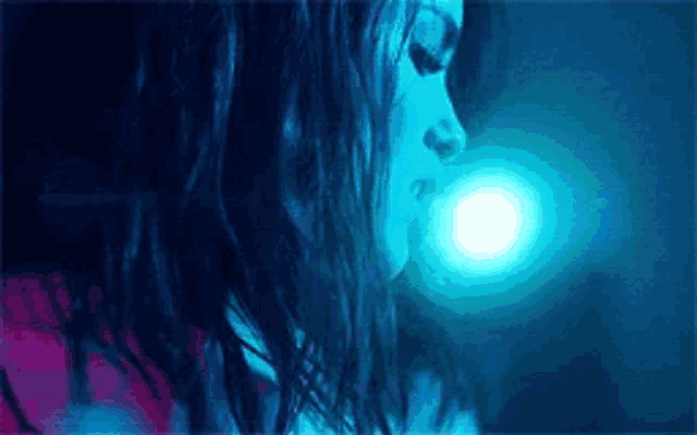 a close up of a woman 's face in a blue light .