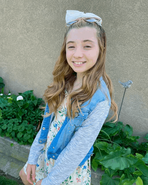 a young girl wearing a floral dress and a denim jacket