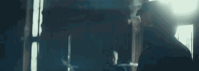 a man is standing in front of a window in a dark room looking out .