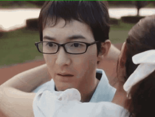 a man wearing glasses is being kissed by a girl