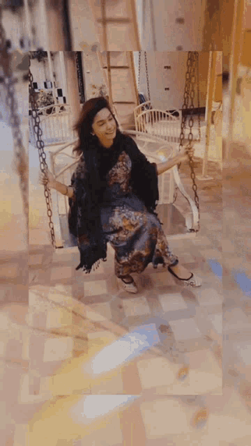 a woman in a dress is sitting on a chain swing