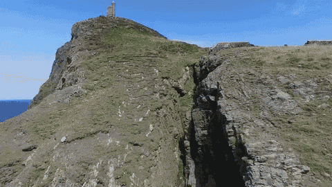 a cliff with a tower on top of it and a hole in it