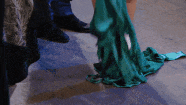 a woman in a long green dress is standing on a wooden floor