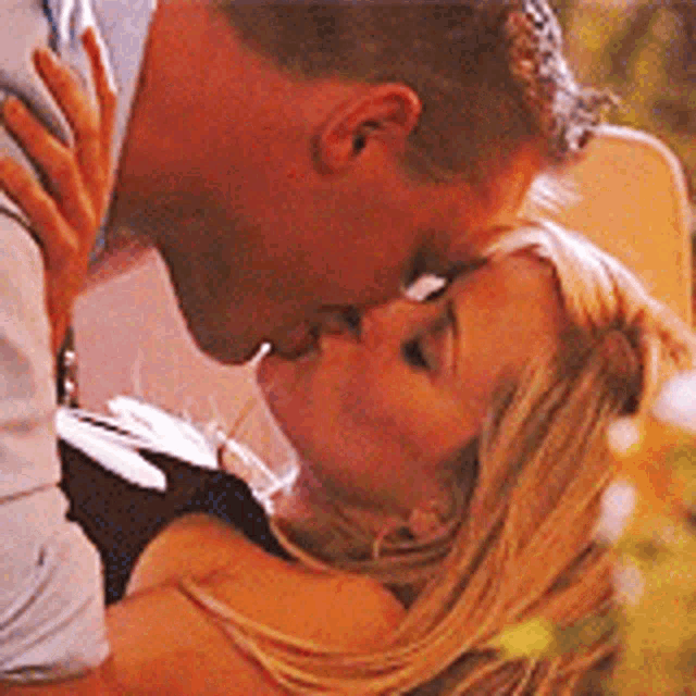 a man and a woman are kissing in front of a tree