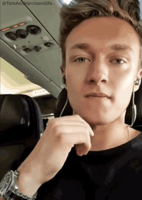 a young man sitting on an airplane with the words tom and harrison gifs above him