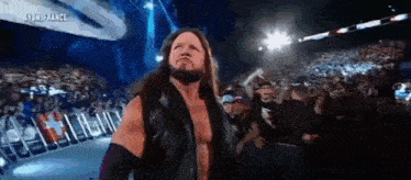 a bearded wrestler is standing in front of a crowd in a stadium .