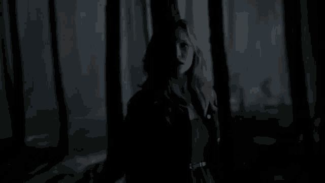 a woman is standing in the dark in a forest .