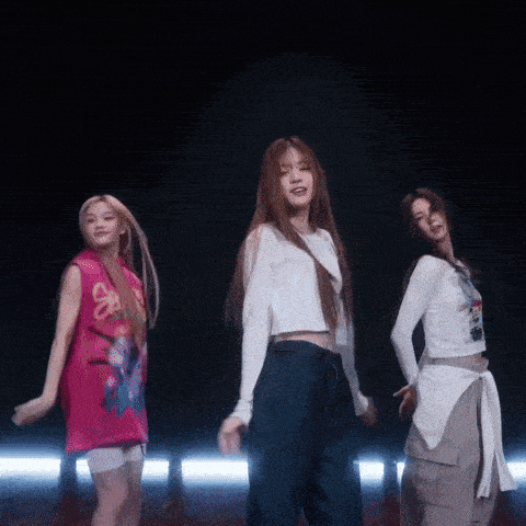 three girls are dancing in a dark room and one has a shirt that says spongebob on it