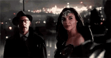 a woman in a wonder woman costume is standing next to a man in a suit .