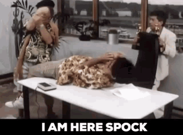a man is laying on a table with the words `` i am here spock '' on the bottom .