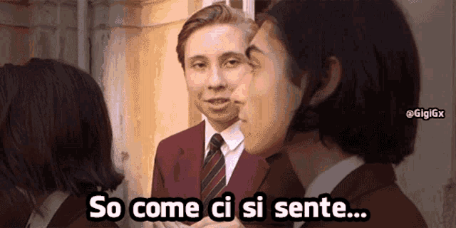 a man in a suit and tie is talking to two women with the words so come ci si sente below him