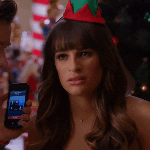 a woman wearing an elf hat is holding a cell phone with a screen that says samantha on it