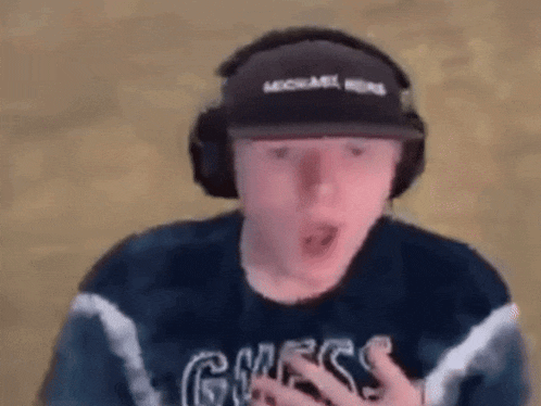 a man wearing headphones and a hat is making a surprised face .