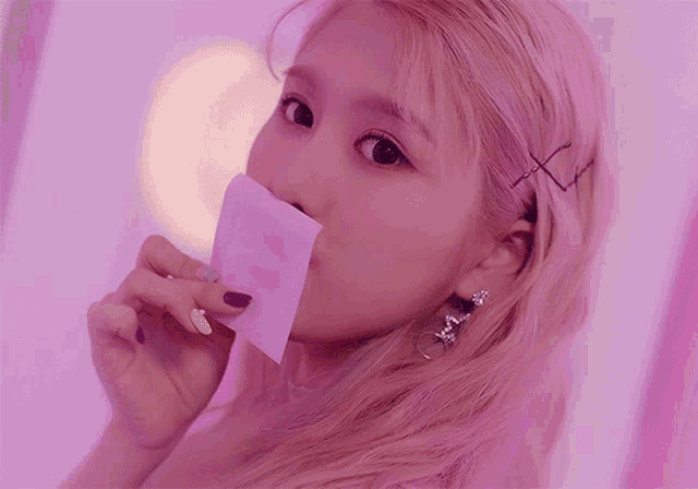 a close up of a woman holding a piece of paper in her mouth