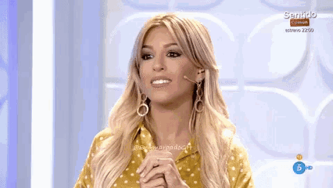 a woman wearing a yellow polka dot shirt and earrings is on a television show