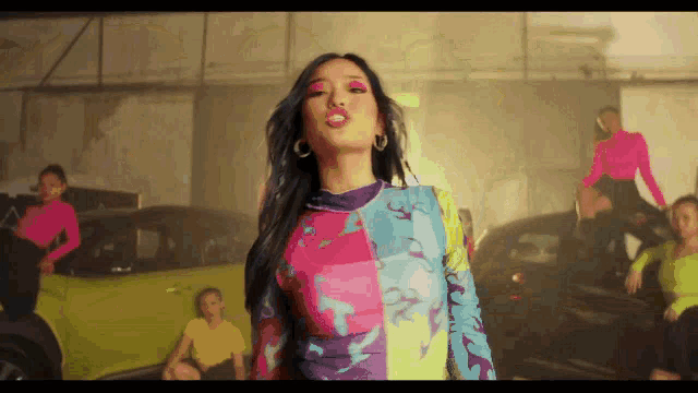 a woman in a colorful top stands in front of a group of people