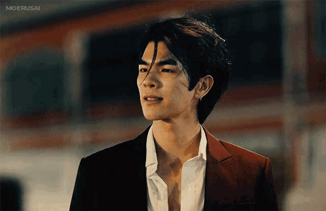 a man in a suit and white shirt is standing in front of a building that says moerusai