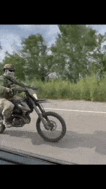 a man is riding a dirt bike on a road with trees in the background