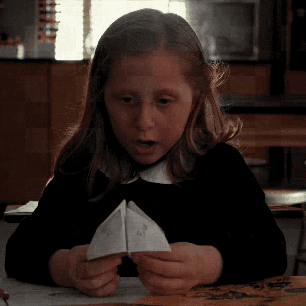 a little girl is playing with a piece of paper that says erica