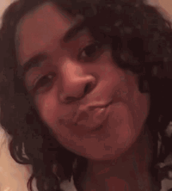 a young woman with curly hair is making a funny face with her mouth open .
