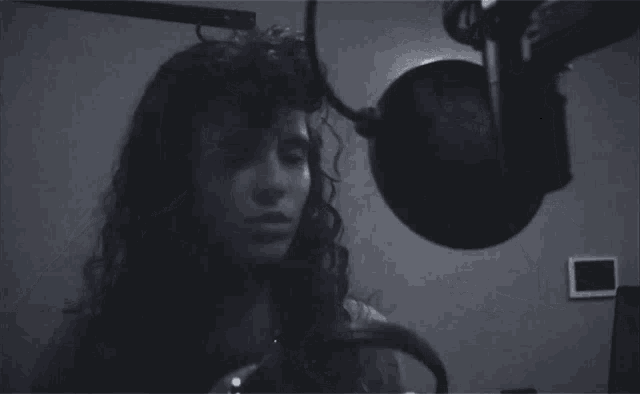 a woman is singing into a microphone in a black and white photo