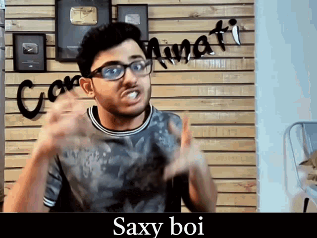 a man wearing glasses stands in front of a sign that says ' saxy boi ' on it