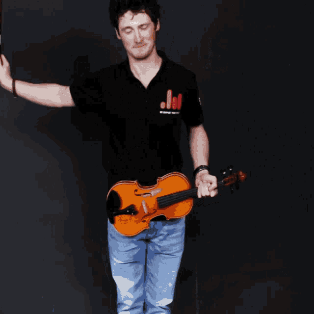 a man is holding a violin and wearing a black shirt that says j.l.i.