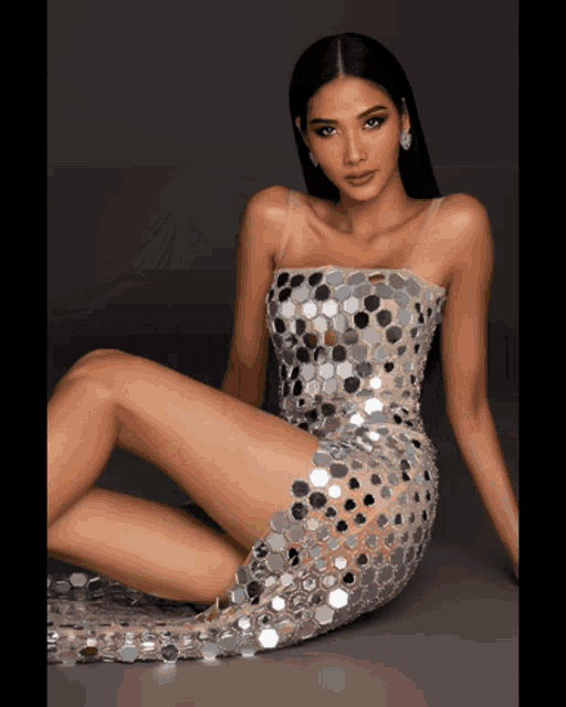 a woman in a sequined dress is sitting on the floor