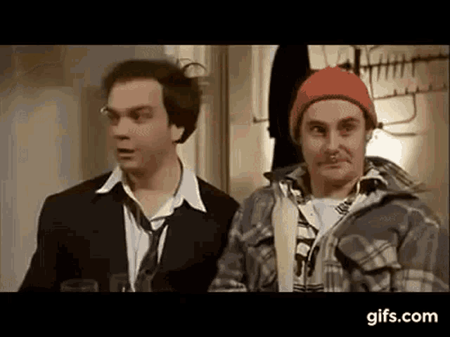 two men are standing next to each other in a room .