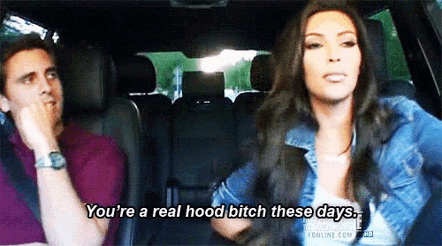 a man and a woman are sitting in a car and the woman is saying you 're a real hood bitch these days