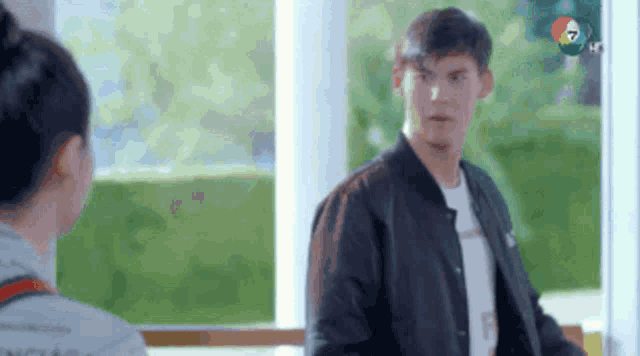 a man in a black jacket is talking to a woman in a white shirt .