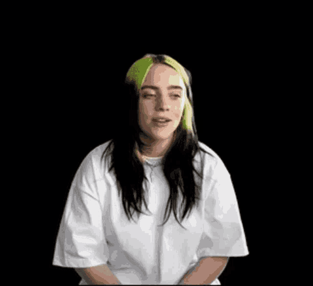 billie eilish is wearing a white t-shirt with green hair .