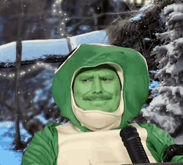 a man with green paint on his face is sitting in front of a microphone in a snowy forest