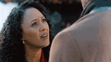 a woman with curly hair looks at a man with a serious look on her face
