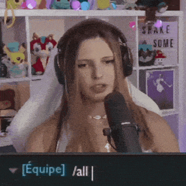 a woman wearing headphones is talking into a microphone with a sign that says shake some on it