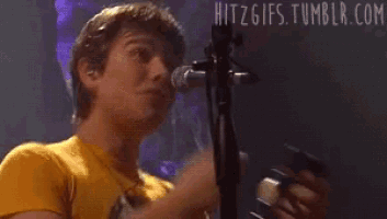 a man singing into a microphone with the website hitzgifs.tumblr.com visible