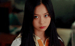 a young girl with long black hair is looking at the camera .