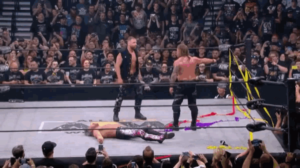 a wrestler is laying on the ground in a wrestling ring while a crowd watches