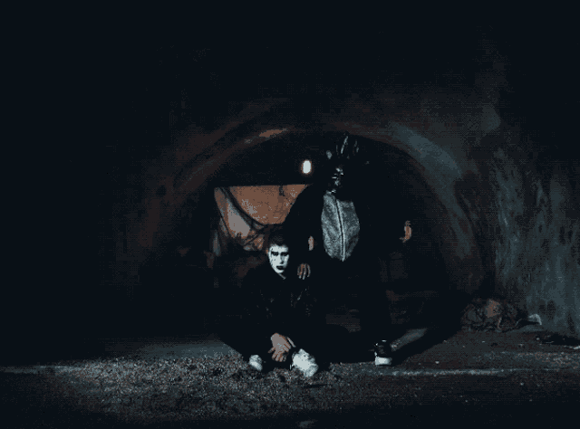 a man in a mask sits next to another man in a mask
