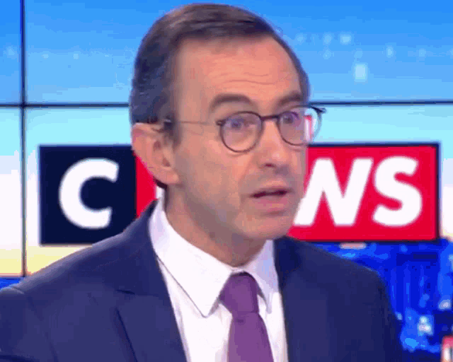 a man in a suit and tie is standing in front of a c news sign
