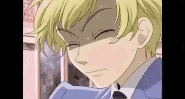 a close up of a cartoon character with blonde hair and a blue suit and tie .