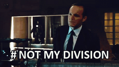 a man in a suit and tie is standing in front of a sign that says " not my division "