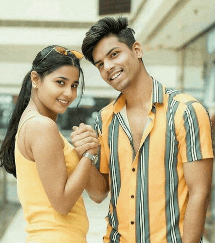a boy and a girl are holding hands and smiling for the camera