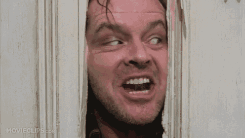 a man is sticking his head through a hole in a door and smiling .