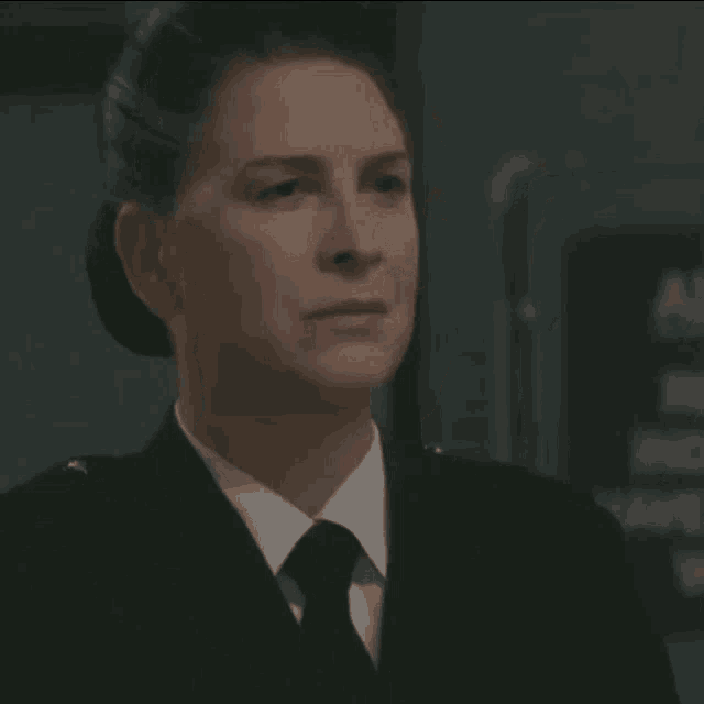a woman in a military uniform and tie is looking at something
