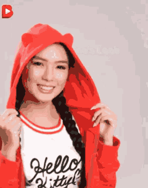 a girl wearing a red hoodie with ears and a white shirt that says hello kitty