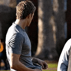 a man in a grey t-shirt is standing in front of a group of people .