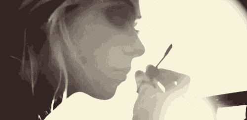 a black and white photo of a woman applying makeup with a mascara