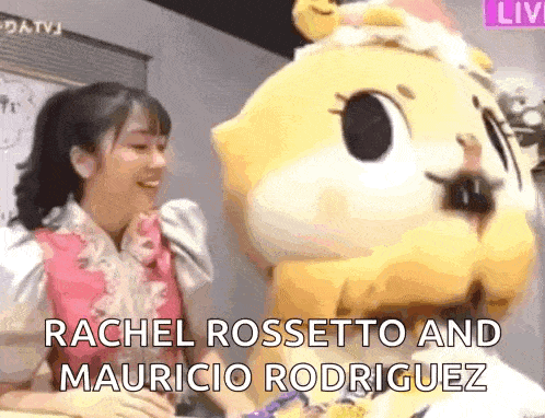 a woman in a pink dress is talking to a mascot .